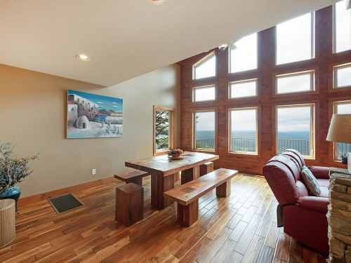 Cozy living area with large windows, wooden furniture, and a scenic view of nature.