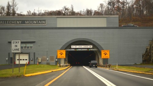 Entrance to the Allegheny Mountain tunnel, with warning signs and traffic lanes visible.