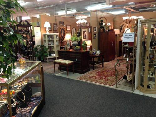 A cozy antique shop filled with furniture, decor, and jewelry displays, featuring warm lighting and a welcoming atmosphere.