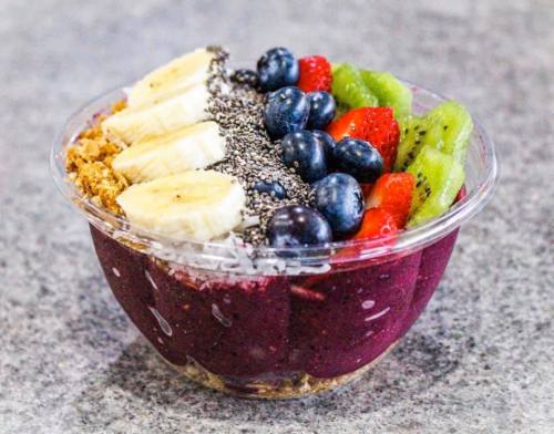 A colorful acai bowl topped with banana, strawberries, blueberries, kiwi, chia seeds, and granola.