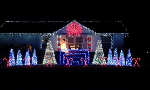 A house decorated with colorful Christmas lights, featuring trees, candy canes, and a large snowman.