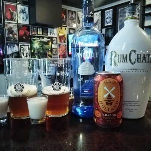 A bar scene featuring two glasses of beer, shot glasses, and bottles of Pinnacle Whipped Vodka, RumChata, and Ichabod Pumpkin Ale.