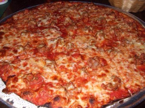 A large pizza topped with melted cheese and chunks of sausage on a red tomato sauce base.