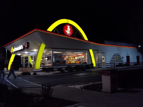 A brightly lit McDonald's restaurant at night, featuring the iconic golden arches and a colorful exterior.