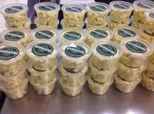 Containers of cheese curds stacked neatly on a table, each labeled with "MANWARING."