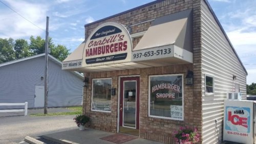 Exterior of Crabill's Hamburgers, a brick building with a sign, flowers, and a clear blue sky.