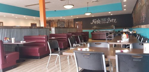 Interior of a casual restaurant featuring booths, tables, and a salad bar, with colorful walls and a welcoming atmosphere.