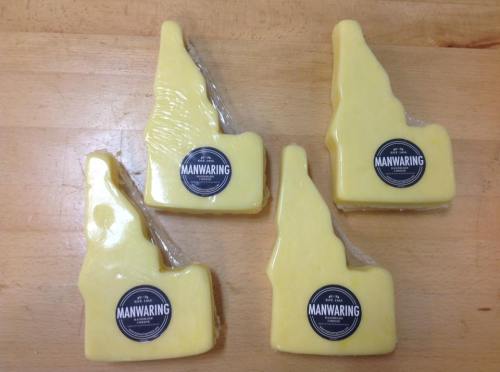 Four pieces of yellow cheese shaped like the state of Idaho, each with a black label reading "MANWARING."