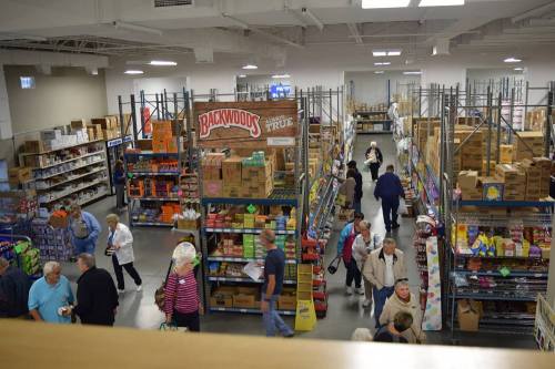 A busy store interior with shelves stocked with various products and shoppers browsing the aisles.