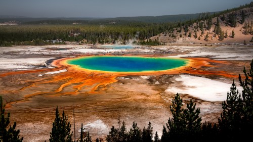 Aerial view of Yellowstone's Grand Prismatic Spring, showcasing vibrant blue water surrounded by orange and yellow mineral deposits.
