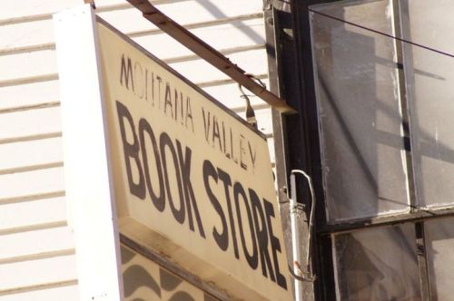 Sign for "Montana Valley Book Store" on a building, with a partially visible window in the background.