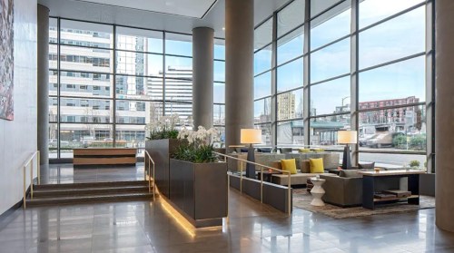 Modern hotel lobby with large windows, stylish seating, and decorative plants, creating a bright and inviting atmosphere.