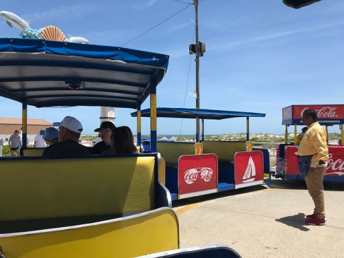 A colorful outdoor seating area with people enjoying drinks, featuring Coca-Cola branding and a clear blue sky.