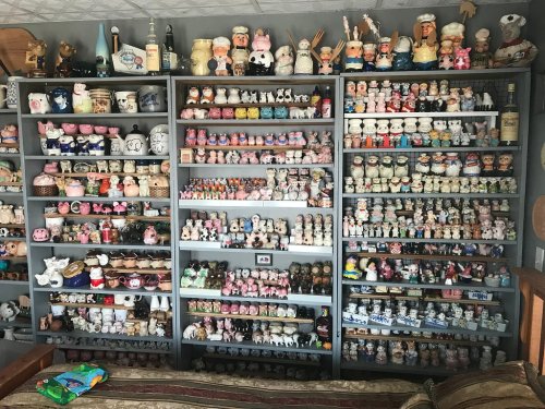 A collection of various ceramic figurines displayed on shelves, featuring animals, people, and decorative items.