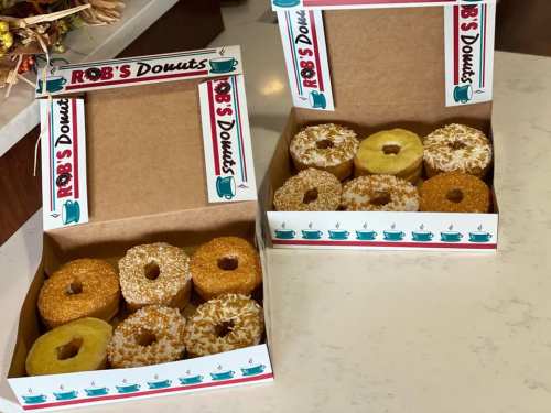 Two boxes of assorted donuts from Rob's Donuts, featuring various toppings and flavors on a countertop.