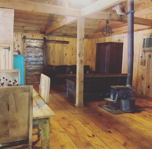 Cozy wooden cabin interior with a rustic stove, wooden furniture, and warm lighting.