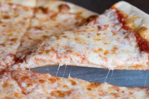 A close-up of a cheese pizza slice being lifted, with melted cheese stretching from the pie.