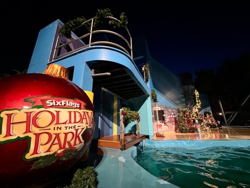 A festive scene at Six Flags featuring a large holiday ornament and decorated pool area at night.