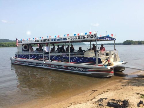 A colorful tour boat with passengers, docked on a riverbank, promoting Mississippi River boat tours.
