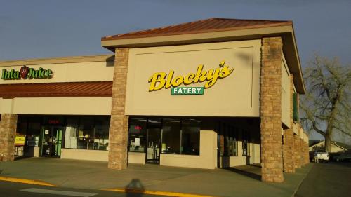 Exterior of Blocky's Eatery, a restaurant with a stone facade, next to Inta Juice, under a clear sky.