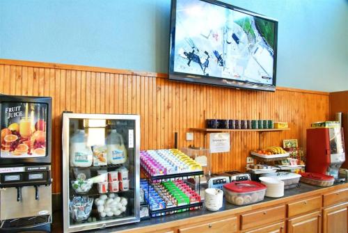 A beverage station with juice dispensers, snacks, and a TV displaying an airport scene on the wall.