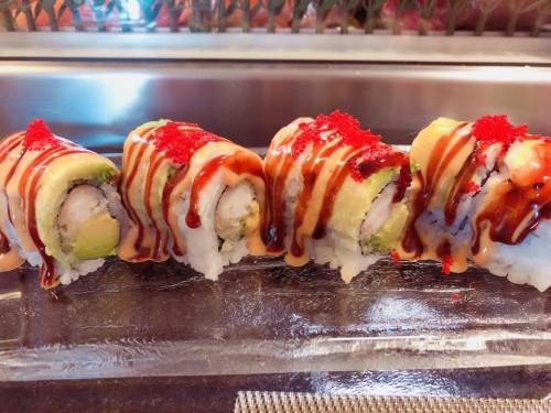 A close-up of colorful sushi rolls topped with sauce and fish roe, arranged neatly on a glass plate.