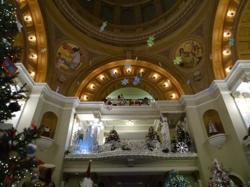 A beautifully decorated hall with Christmas trees, snowflakes, and festive lights under a grand dome.