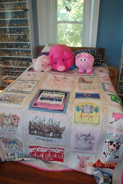 A bed with a colorful quilt featuring pig-themed designs, topped with two plush pig toys.