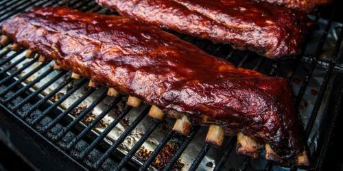 Close-up of juicy, glazed barbecue ribs sizzling on a grill, showcasing a rich, caramelized exterior.