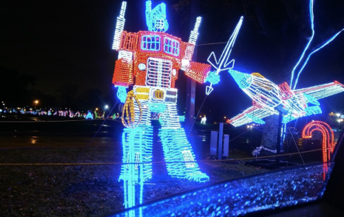 A colorful light display featuring a robot figure holding a sword, set against a dark night sky.