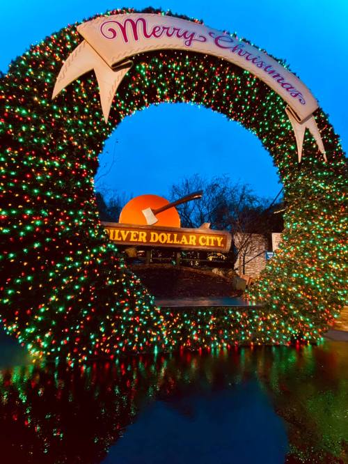 A festive archway adorned with colorful lights and a "Merry Christmas" sign at Silver Dollar City.