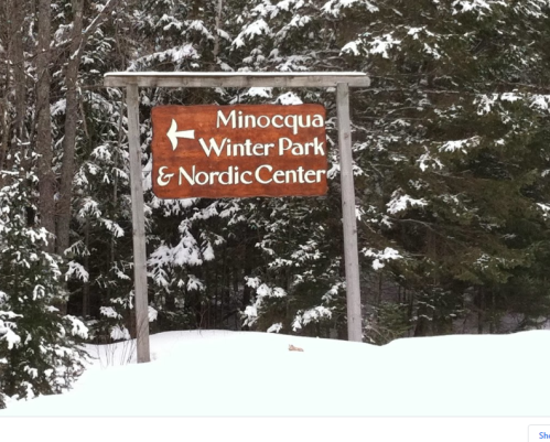 Sign for Minocqua Winter Park & Nordic Center, surrounded by snow-covered trees.