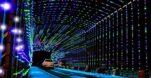 A brightly lit tunnel adorned with colorful lights in blue, green, and pink, creating a festive atmosphere.