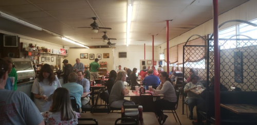 A busy diner with people dining at tables, chatting, and enjoying their meals in a casual setting.