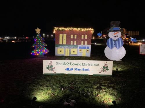 A festive display featuring a decorated Christmas tree, a snowman, and a sign for "An Olde Towne Christmas."