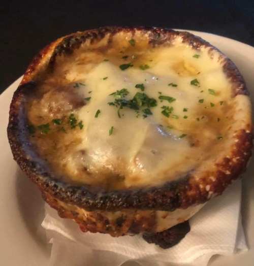 A baked dish with melted cheese and herbs, served in a crispy, golden-brown bowl.