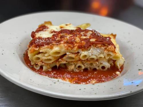 A serving of baked pasta with marinara sauce and cheese on a white plate, garnished with herbs.