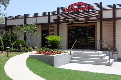 Exterior view of a building with "Coast Catfish" signage, featuring landscaped gardens and a pathway leading to the entrance.