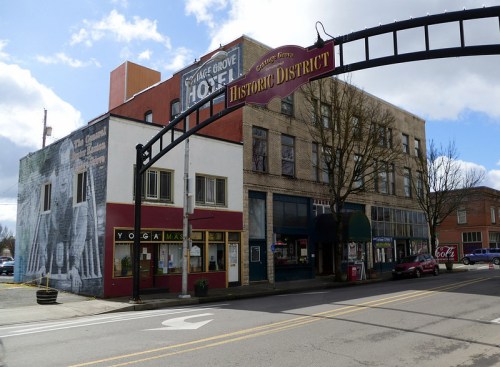 Historic District entrance with buildings, including a yoga studio and a mural, under a partly cloudy sky.