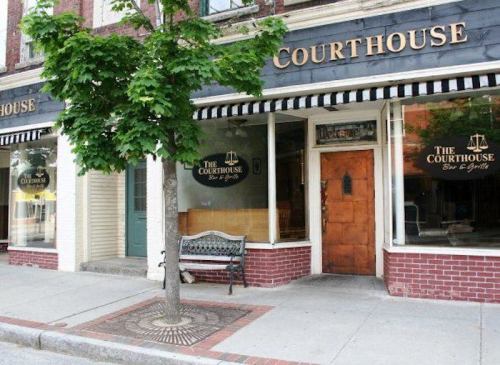 Exterior of a restaurant named "The Courthouse Bar & Grill," featuring large windows and a tree in front.