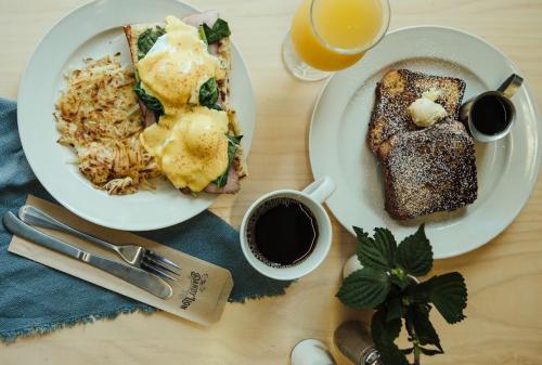A breakfast spread featuring eggs Benedict, hash browns, French toast, coffee, and a glass of orange juice.