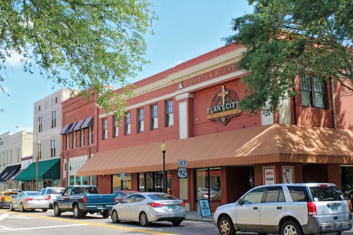 A street view of a historic building in Plant City, featuring shops and parked cars under a clear blue sky.