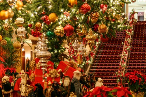 A festive holiday scene featuring a decorated Christmas tree, colorful ornaments, and Santa figurines near a staircase.
