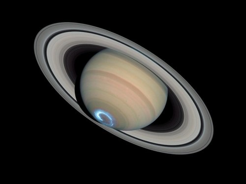 A stunning view of Saturn, showcasing its rings and a bright blue polar region against a black background.