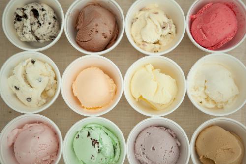 A variety of ice cream flavors in small cups, arranged in a grid pattern on a light background.