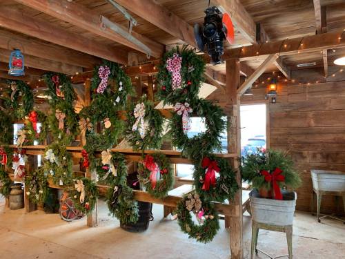 A rustic wooden barn interior decorated with festive wreaths and holiday lights.