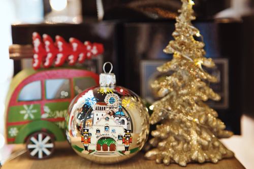 A festive scene featuring a decorative ornament, a small golden tree, and a colorful holiday-themed vehicle.