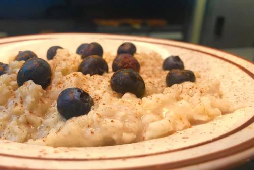 A bowl of creamy oatmeal topped with fresh blueberries and a sprinkle of cinnamon.