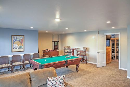 A cozy game room featuring a pool table, foosball table, seating area, and a wine cellar in the background.