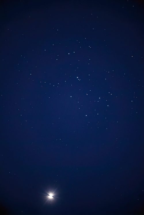 A night sky filled with stars, featuring a bright celestial object in the lower left corner.